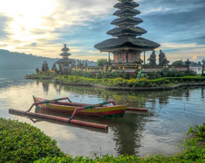canoe on body of water with pagoda background