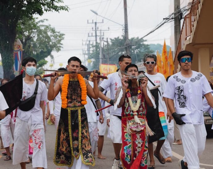 Participants in a vibrant Thai vegetarian festival parade through the streets of Phuket.