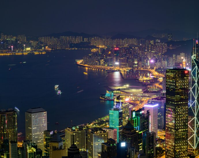 Stunning nighttime view of Hong Kong Island with illuminated skyscrapers and vibrant cityscape across Victoria Harbor.