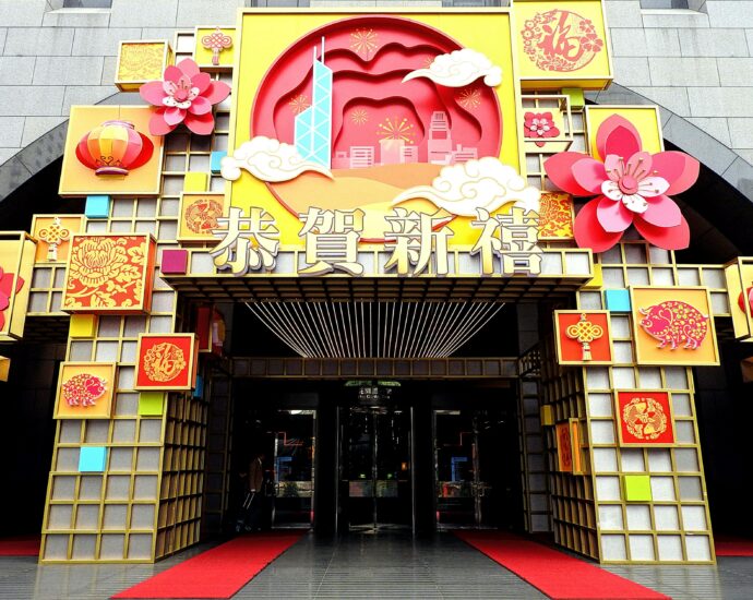 Exterior of colorful Asian building decorated with signboards and hieroglyphs near decorative elements in town street in daylight near entrance on pavement