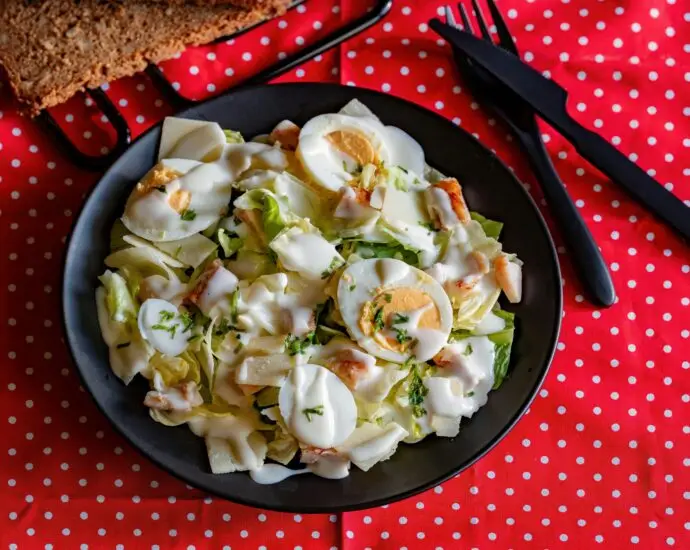 A delicious Caesar salad featuring romaine, eggs, and creamy dressing on a vibrant polka dot cloth.